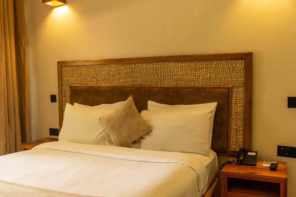 King bed with woven headboard in a room at Mvuli Farm Lodge