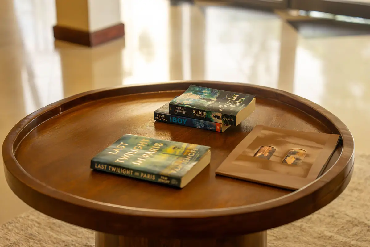 Books on a round wooden side table at Mvuli Farm Lodge